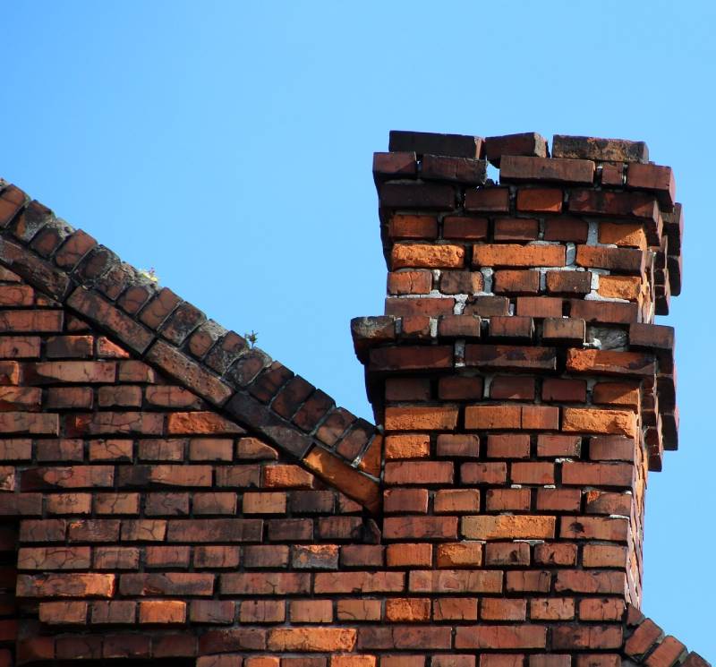 Damaged chimney on an Newport Beach home showing cracks and missing mortar